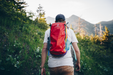 Individual trekking in the woods with the Cotopaxi Batac backpack secured