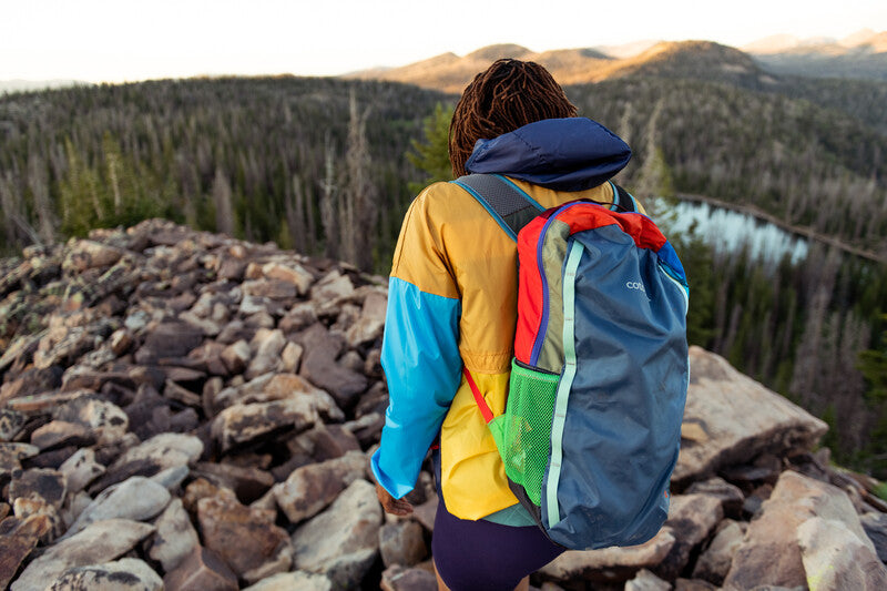 Adventurer wearing a Cotopaxi Batac backpack while trekking on a mountain trail