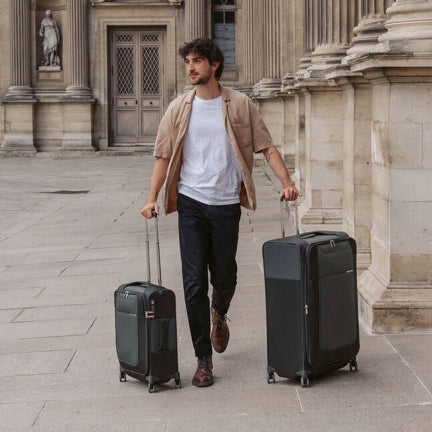 Individual walking on the street with a Samsonite D'Lite Large Spinner suitcase