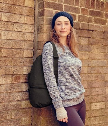 Lifestyle shot of a person leaning against a wall while wearing the AmeriBag Healthy Back Bag