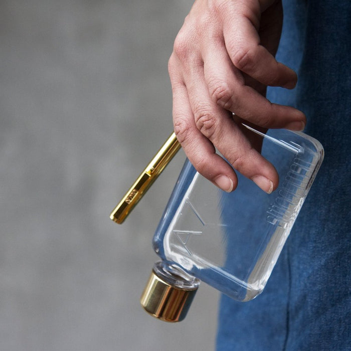 A person gripping the A7 Memobottle 180ml with a transparent and sleek design