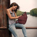 Casual image of a woman resting on a bridge with the AmeriBag slung over her shoulder