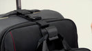 Close-up of a hand attaching the Add-A-Bag strap to a black suitcase